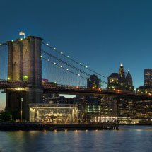 Brooklyn bridge with lights and New York City behind